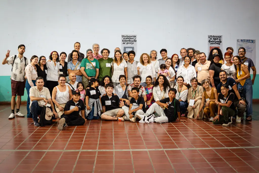 Grupo diverso reunido en "La Siembra" para regeneración del territorio. Pancartas sobre restauración ecológica y gobernanza del agua.