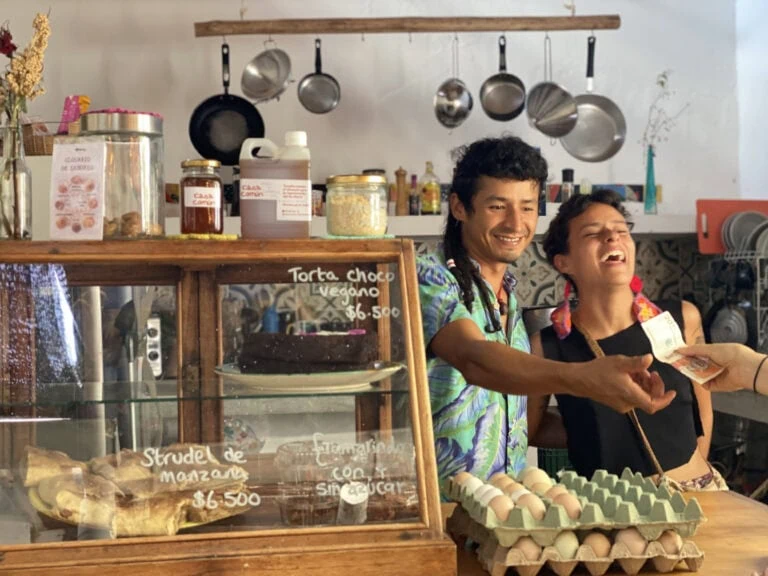 En Casa Común, una pareja sonríe al recibir un pago por torta vegana y strudel de manzana.
