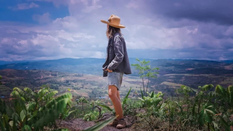 Mujer con sombrero en la Reserva Natural Origen del Agua, admirando el paisaje montañoso.