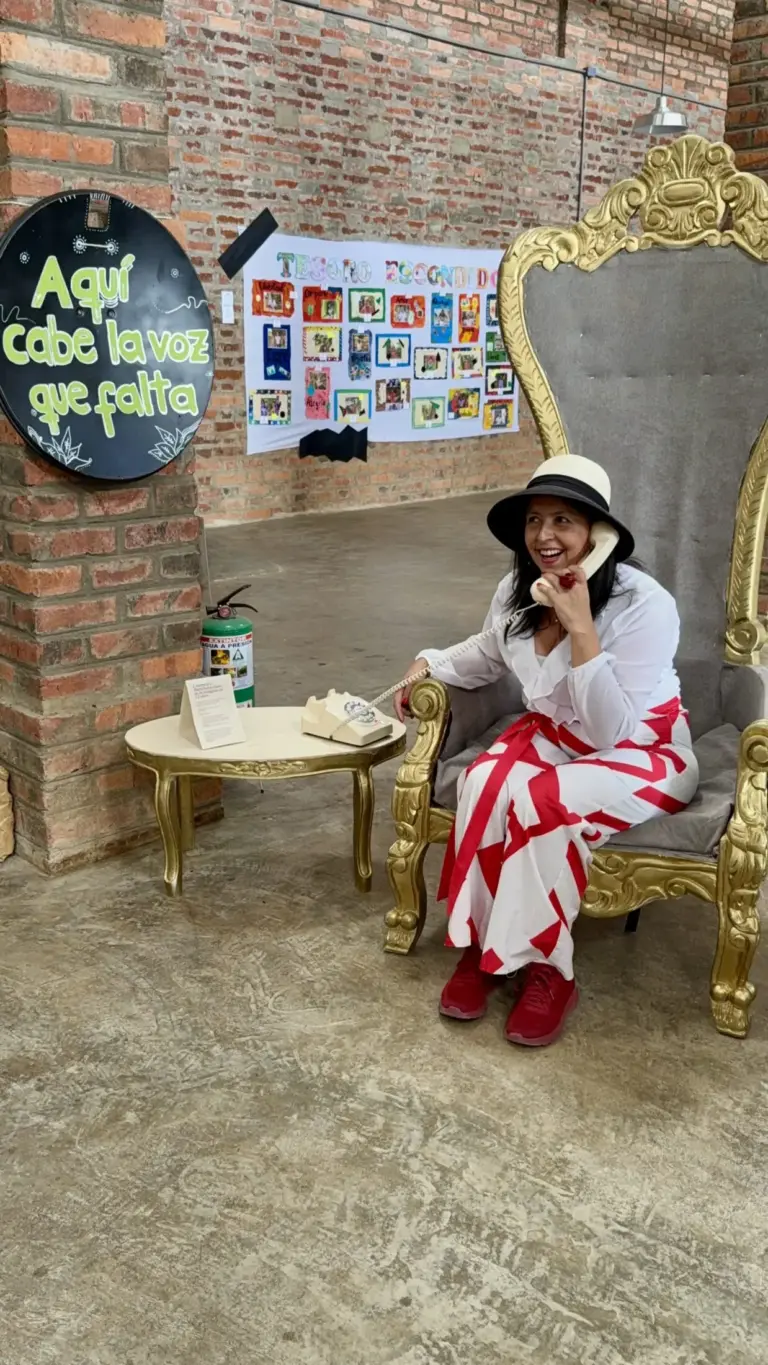 Mujer sonriendo en trono dorado hablando por teléfono antiguo. Letrero: "Aquí cabe la voz que falta".