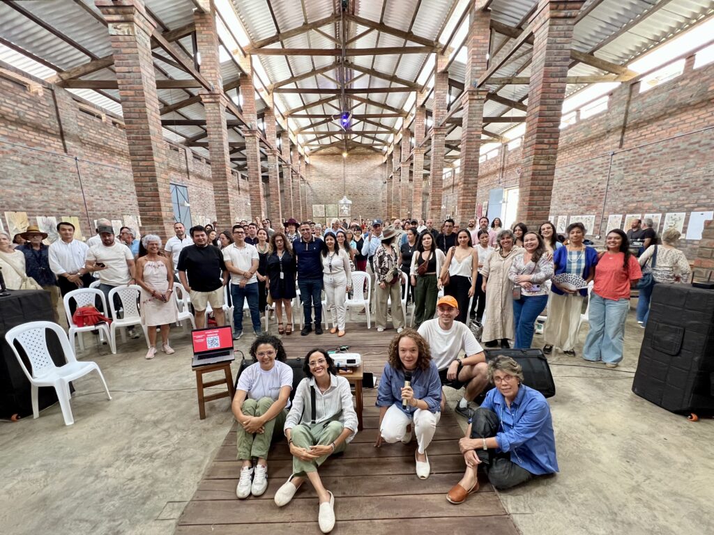 Grupo grande reunido en espacio abierto con vigas de madera y ladrillo a la vista.