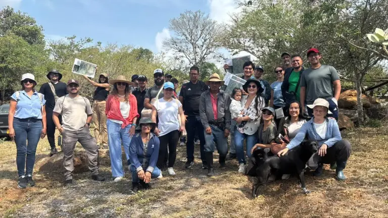 Grupo diverso en intercambio Kairigua y Rizoma, con mapas y perro negro.