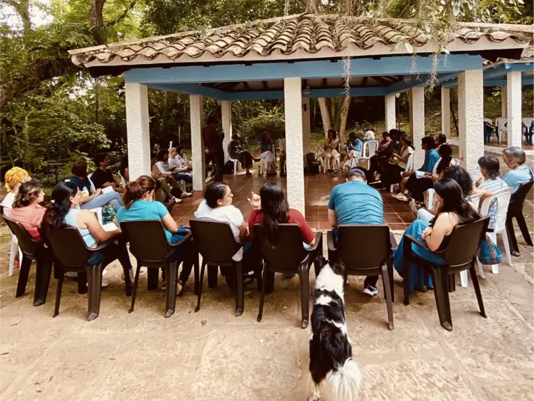 Grupo diverso reunido en un pabellón al aire libre para una discusión grupal.