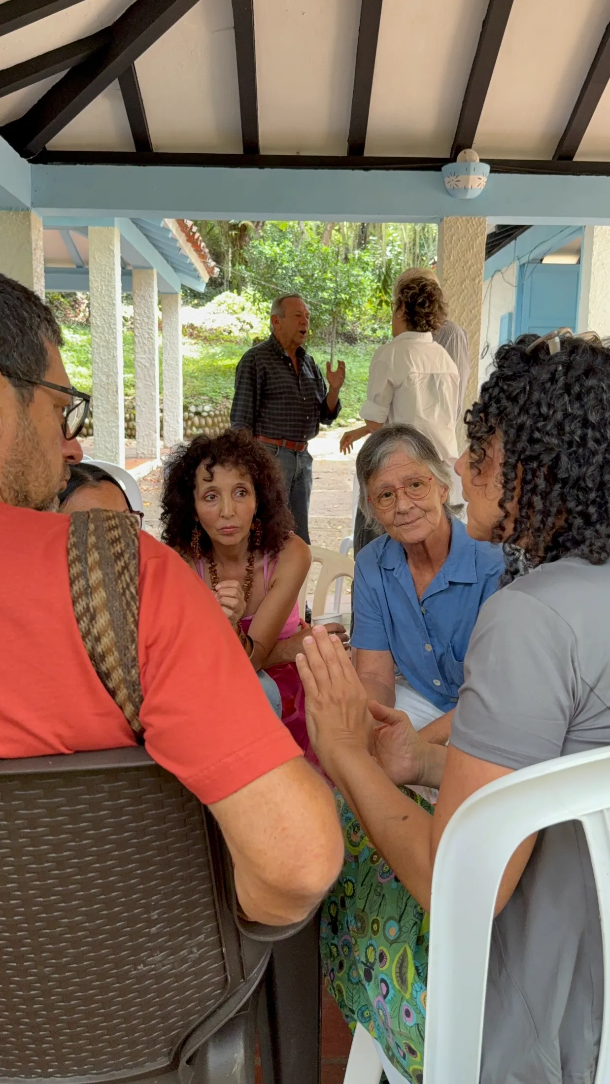 Grupo de personas mayores conversando animadamente en un encuentro al aire libre.