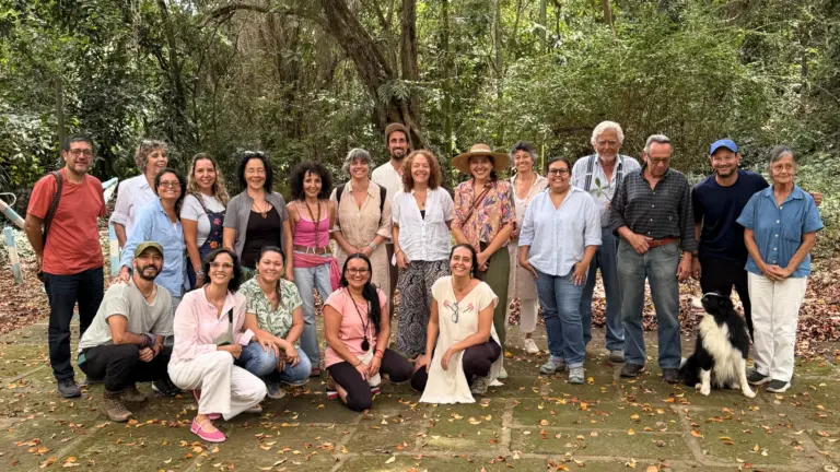 Grupo diverso de personas posando para una foto grupal al aire libre con un perro.