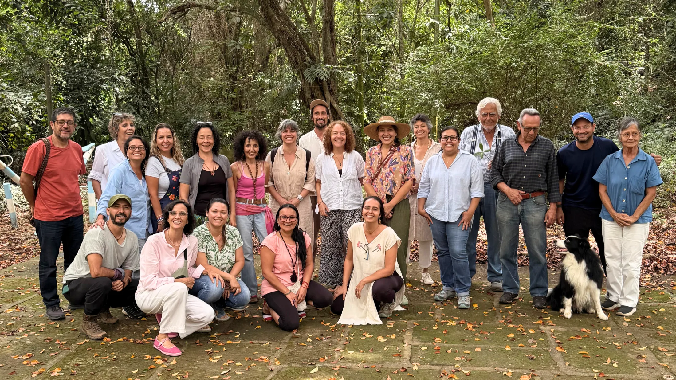 Grupo diverso de personas posando para una foto grupal al aire libre con un perro.